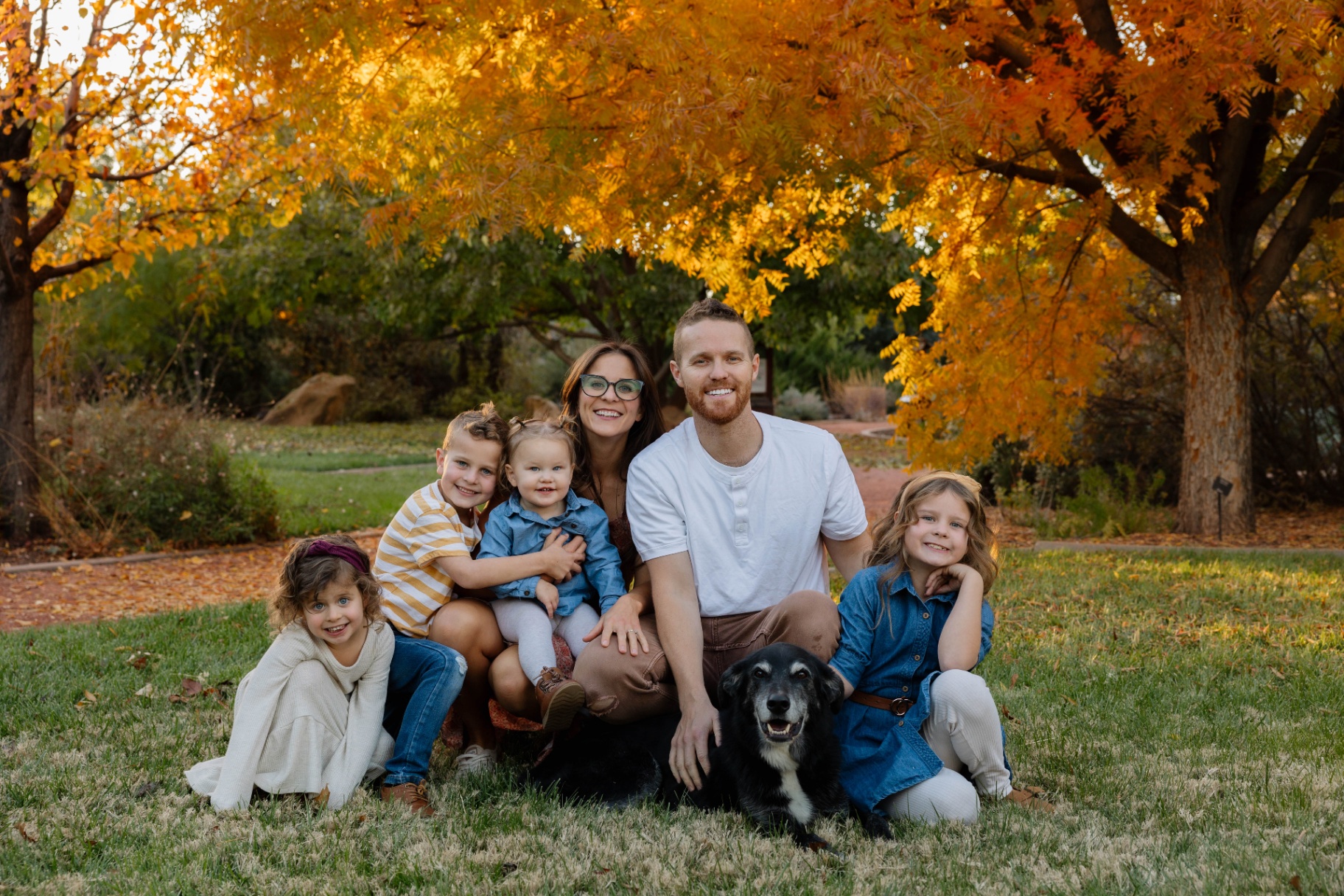 Remington Carlson with his wife Alyssa, their four children, and their dog under an autumn tree.
